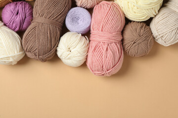 Fototapeta na wymiar Soft woolen yarns on beige background, flat lay. Space for text