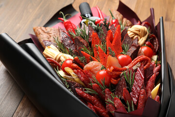 Beautiful edible bouquet with meat, cheese and vegetables on wooden table, closeup
