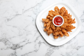Fried blooming onion with dipping sauce served on white marble table, top view. Space for text