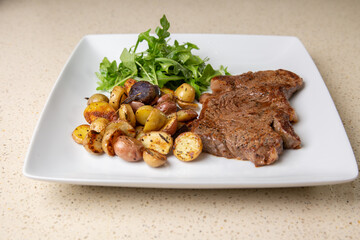 Rib eye steak with cut potatoes in green salad 