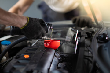 Pouring oil to car engine. Closue up male mechanic hand working  and service in Car Service station