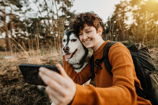 Junger Mensch macht Selfie mit Hund in der Natur 