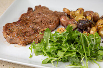 Rib eye steak with cut potatoes in green salad 