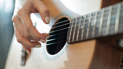 Fototapeta premium Close-up of female hands on an acoustic guitar. The girl learns to play the guitar