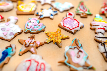 Hand decorated baked gingerbreads of various shapes, arranged on baking paper.