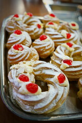 Italian pastry - zeppole di San Giuseppe - baked cream puffs made from choux pastry, filled and decorated with custard cream and cherry. It is eaten to celebrate Saint Joseph's Day.  Selective focus