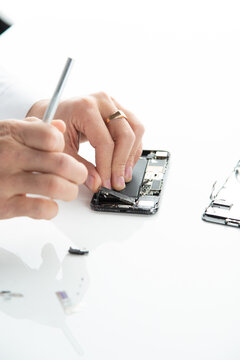 Phone repair process on a white background. Disassembled phone, battery replacement, broken screen, service.