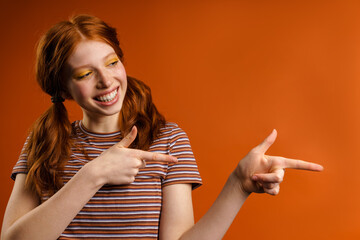 Ginger cheerful woman with tails smiling and pointing fingers aside