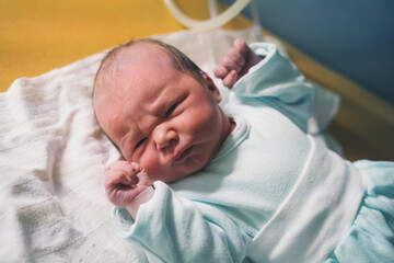 Newborn baby after delivery in labor room. Doctor and midwife examining newborn boy after birth in hospital.