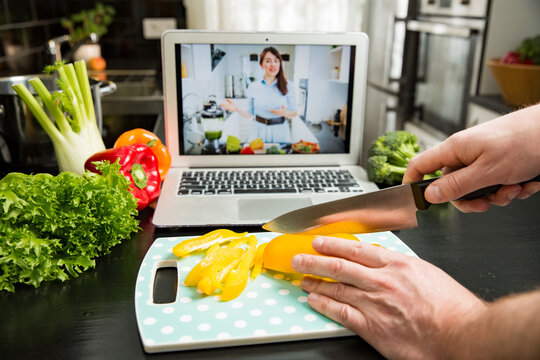 Beautiful happy woman streaming broadcast video blog about tasty and healthy food from home kitchen. Healthy lifestyle and social media. Man watching video recipe on laptop and cooking at home.