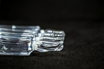 Glass medical ampoule vial for injection. Medicine is liquid sodium chloride with of aqueous solution in ampulla. Close up. Bottles ampule multicolor on background color and water. Human plasma.