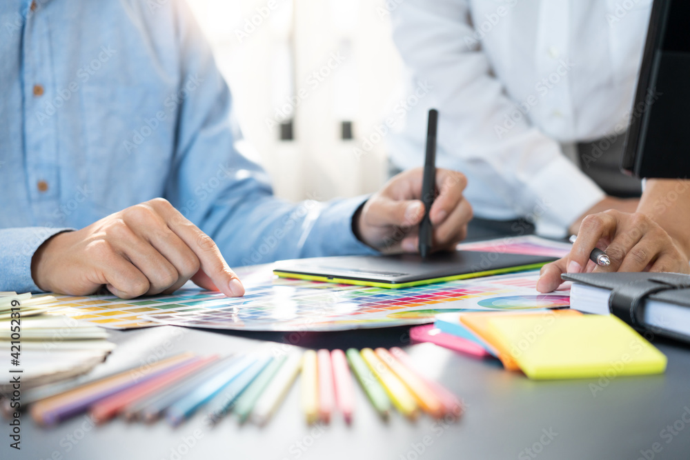 Poster graphic designer team working on web design using color swatches editing artwork using tablet and a 