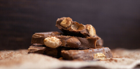 Broken pieces of chocolate and cocoa powder on wooden background