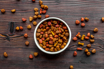 dry dog food in bowl on wooden background top view