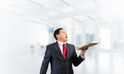 Surprised businessman holding open book