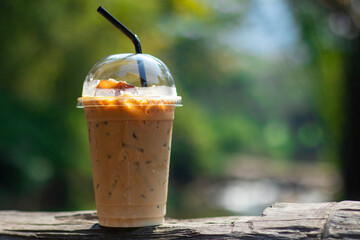 Iced latte Coffee on wood table bokeh nature background in the garden, warm tone, and copy space for text ideas.
