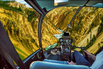 Helicopter cockpit pilot arm flight over Lower Falls, most popular waterfall in Yellowstone, located in head of Grand Canyon in Yellowstone River of Yellowstone National Park, Wyoming, United States.