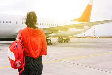 The girl is standing near the plane waiting for departure. Boarding passengers on the flight. Young...
