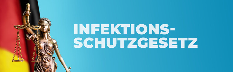 Infektionsschutzgesetz. Justitia Skulptur umgeben von einer Deutschland Flagge vor blauem...