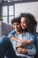 Obraz premium Cheerful african american woman with closed eyes hugging boyfriend