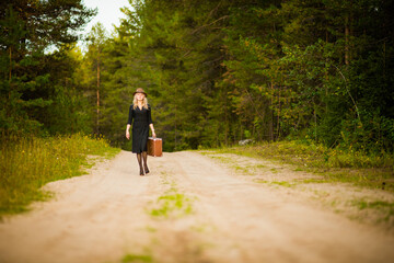 blonde girl in black dress with suitcase, selective focus