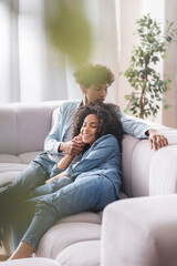 Obraz premium Smiling african american woman lying near boyfriend on couch