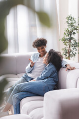 Smiling african american man talking to girlfriend while sitting on couch