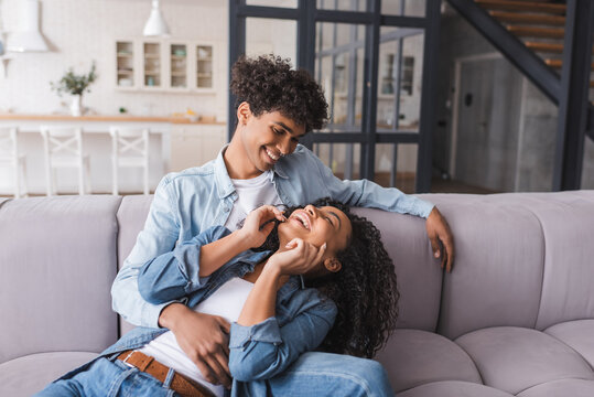 Smiling african american man looking at laughing girlfriend on couch