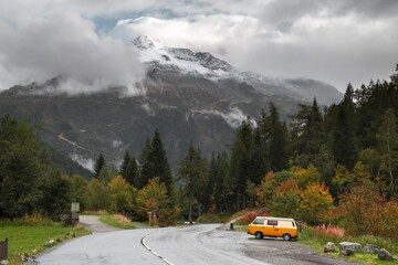 A yellow van is parked for the night on the side of the road with a view of the French Alps