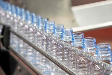 The PET bottles  on the conveyor belt for filling process in the drinking water factory. The hi-technology of plastic bottle manufacturing process.