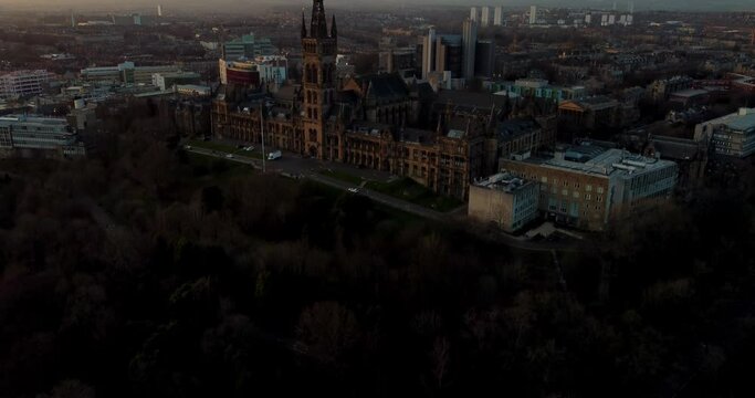 Flying in spring at sunset over the Kelvingrove park in Glasgow, Scotland towards the Gilbert Scott tower at Glasgow University.