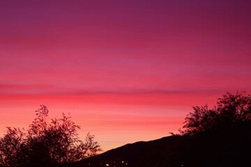 Fototapeta na wymiar Stunning sunset sky with gradient purple afterglow over the silhouette of mountainside