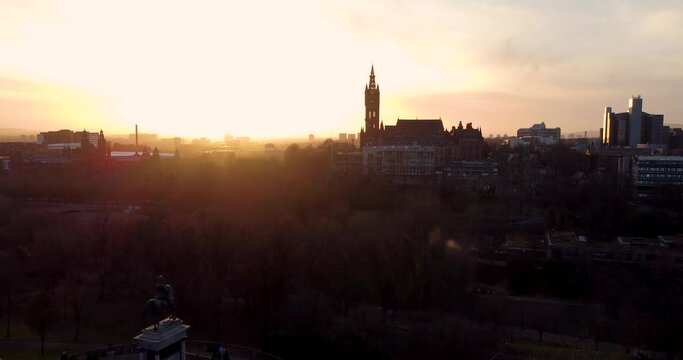 Flying in spring at sunset over the Kelvingrove park in Glasgow, Scotland towards the Gilbert Scott tower at Glasgow University.