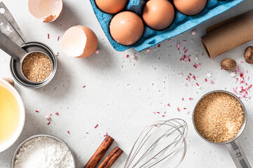 Baking ingredients and kitchen utensils on a white background top view. Baking background. Flour, eggs, sugar, spices, and a whisk on the kitchen table. Flat lay.
