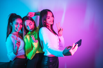 Lifestyle of friends partying in a disco with blue and pink neon lights, taking a selfie with the...