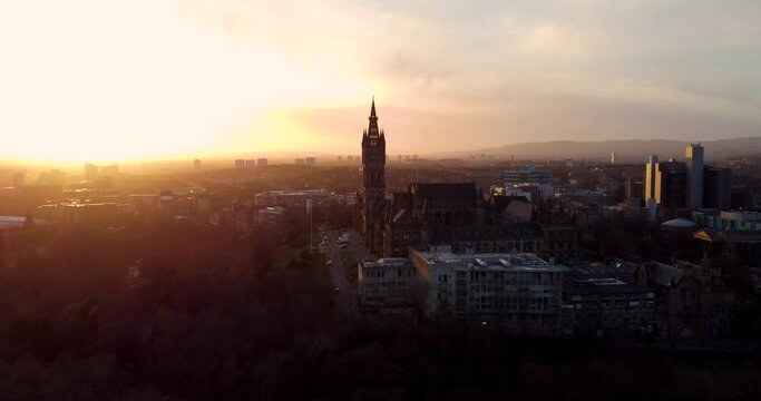 Flying in spring at sunset over the Kelvingrove park in Glasgow, Scotland towards the Gilbert Scott tower at Glasgow University.