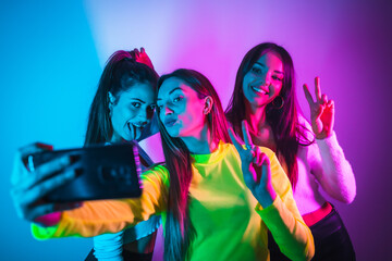 Lifestyle of friends partying in a disco with blue and pink neon lights, having fun taking a photo...