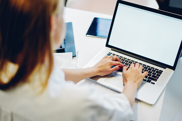 Faceless female freelancer working on computer in workplace