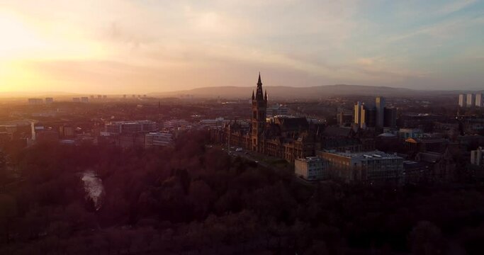 Flying in spring at sunset over the Kelvingrove park in Glasgow, Scotland towards the Gilbert Scott tower at Glasgow University.