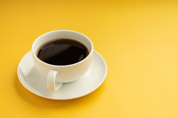 Side view of a white coffee cup is placed on a yellow background. Space for text. Concept of beverage and relaxation