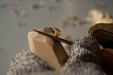 Hands carving wood with pocket knife, wood shavings and gloves - Powered by Adobe