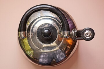 one gray metal kettle with a black whistle stands on a pink table