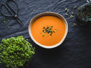 Vegetable creamy healthy soup with pumpkin seeds on a kitchen table.