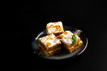 Carrot dessert cake on a plate on a black background.