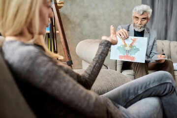 Psychotherapist showing Rorschach test pictures to woman