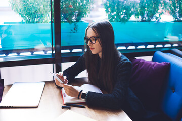 Thoughtful woman typing message on smartphone