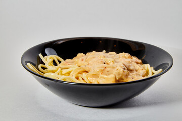 Long spaghetti in a black plate on a white background
