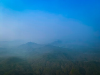 Aerial view of Mountain range surrounded by mist with blue sky 