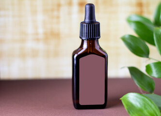 Brown bottle with cosmetic serum for the face on a beige background.