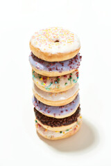 Amazing donut recipe. Tower of various sweet colorful donuts with sprinkles and glaze isolated over light background